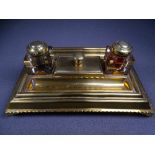 OBLONG BRASS INK STAND on corner supports with centre brass topped blotter and flanking square glass