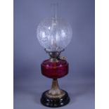 BRASS BASED OIL LAMP having a Cranberry glass reservoir and an etched floral bowl shade
