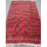 INDIAN RED GROUND WOOLLEN CARPET having a central repeating block pattern and a multi-bordered