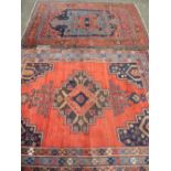 TWO VINTAGE EASTERN WOOLLEN RUGS, red ground with traditional pattern centres and multiple