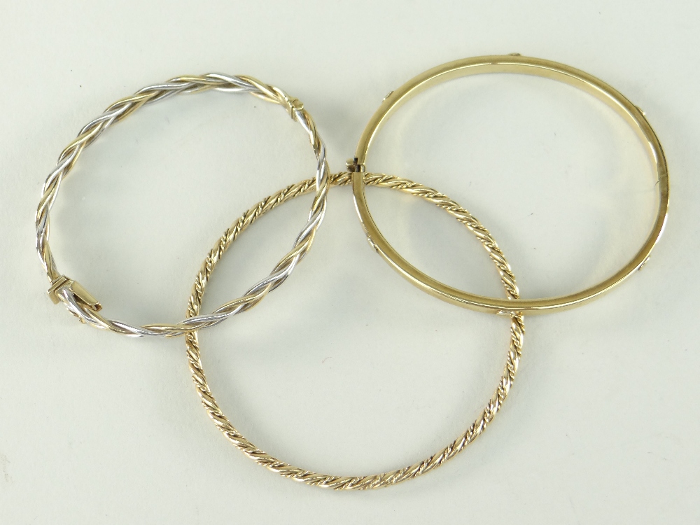 THREE 9CT GOLD LADIES BANGLES, of various design to include spiral and slotted screw head, 26gms