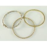 THREE 9CT GOLD LADIES BANGLES, of various design to include spiral and slotted screw head, 26gms