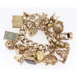 HEAVY 9CT GOLD FLAT CURB LINK CHARM BRACELET having an assortment of mainly 9ct gold charms