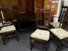 AN ERCOL STAINED ELM ELIZABETHAN-STYLE DINING SUITE comprising high dresser, oval extending dining