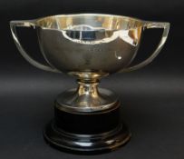 GEORGE V SILVER TWIN-HANDLED PRESENTATION TROPHY CUP, raised on ebonized circular socle base,