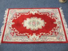 CHINESE WASHED WOOLLEN CARPET red and cream ground with repeating floral bordered pattern and