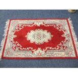 CHINESE WASHED WOOLLEN CARPET red and cream ground with repeating floral bordered pattern and