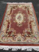 CHINESE WASHED WOOLLEN CARPET, pink ground with multi-colour floral border and central medallion,
