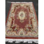 CHINESE WASHED WOOLLEN CARPET, pink ground with multi-colour floral border and central medallion,