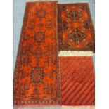 THREE PERSIAN/EASTERN WOOLLEN SCATTER RUGS, all on red grounds in repeating block patterns with