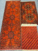 THREE PERSIAN/EASTERN WOOLLEN SCATTER RUGS, all on red grounds in repeating block patterns with