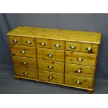 REPRODUCTION PINE CHEST of twelve drawers with brass effect cup handles, 75cms H, 119cms W, 35.