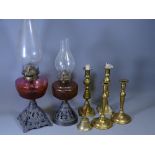 TWO IRON BASED OIL LAMPS, one with Amber glass and one with Cranberry glass reservoirs, two pairs of