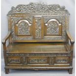 ANTIQUE STYLE OAK CARVED BOX SEAT SETTLE, the top rail with carved initials to the shield over a