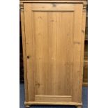 CONTINENTAL STRIPPED PINE SINGLE DOOR WARDROBE with carved detail to the front on turned bun feet,