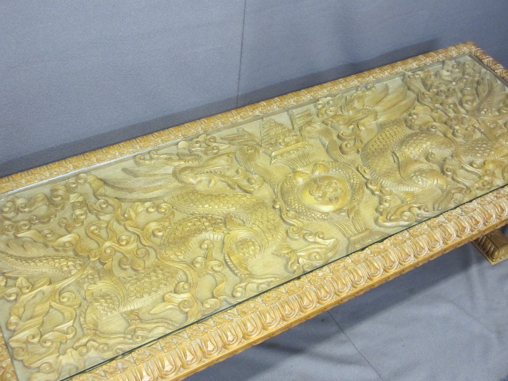 AN EASTERN HEAVILY CARVED LONG-JOHN COFFEE TABLE with a glazed top, 50cms H, 150cms W, 56cms D - Image 2 of 4