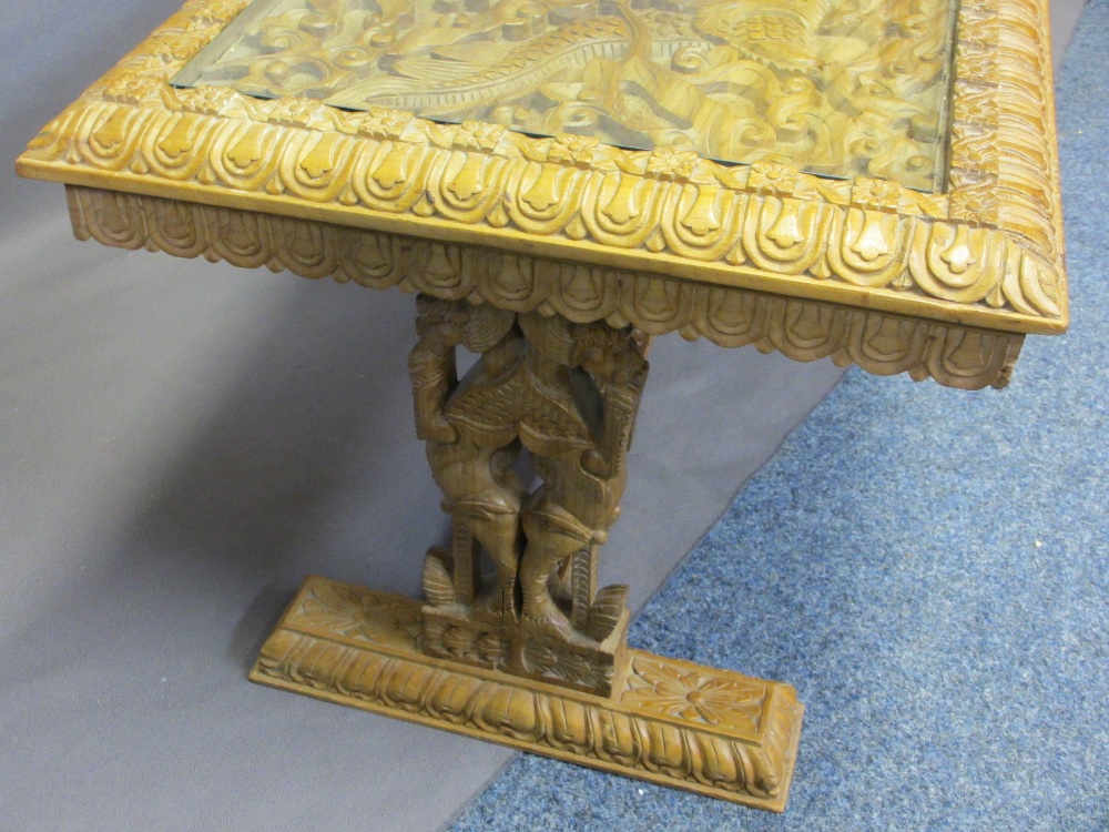 AN EASTERN HEAVILY CARVED LONG-JOHN COFFEE TABLE with a glazed top, 50cms H, 150cms W, 56cms D - Image 3 of 4