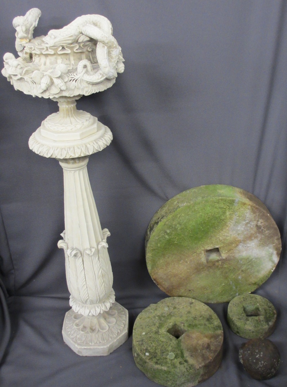 THREE STONE GRINDING WHEELS, composition planter on stand and an iron cannonball remnant, the