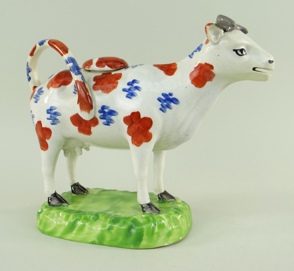 A SWANSEA CAMBRIAN POTTERY COW CREAMER with tail as loop handle, standing on a moulded oval base,