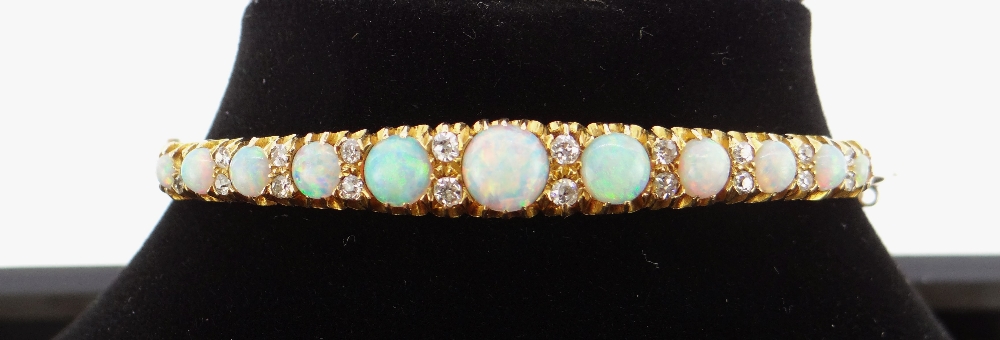 15CT GOLD OPAL & DIAMOND BANGLE, the eleven graduating opals alternating with graduating pairs of