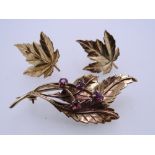 A 9CT GOLD LEAF BROOCH with four garnets and a pair of screw-fit nine carat gold earrings, total