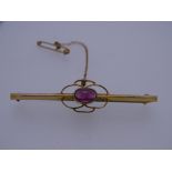 A 9CT GOLD BAR BROOCH with centre oval garnet, 2.2grms