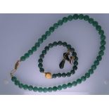 A JADE NECKLACE ENSEMBLE - a dark green jade bead necklace with yellow metal, believed nine carat