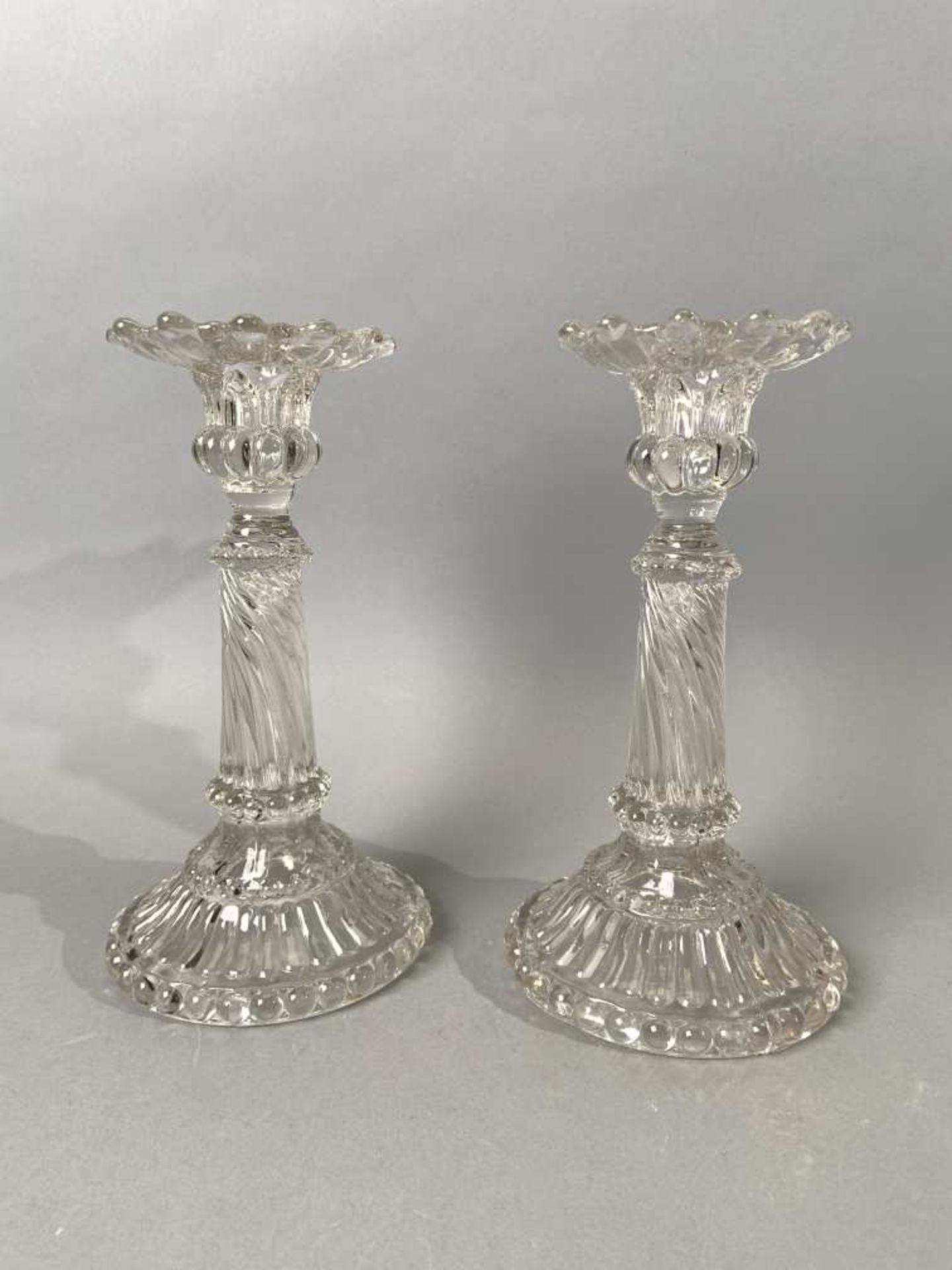 Dans le goût de BACCARAT. Deux bougeoirs en verre moulé-pressé, le fut en colonne torsadée. H.