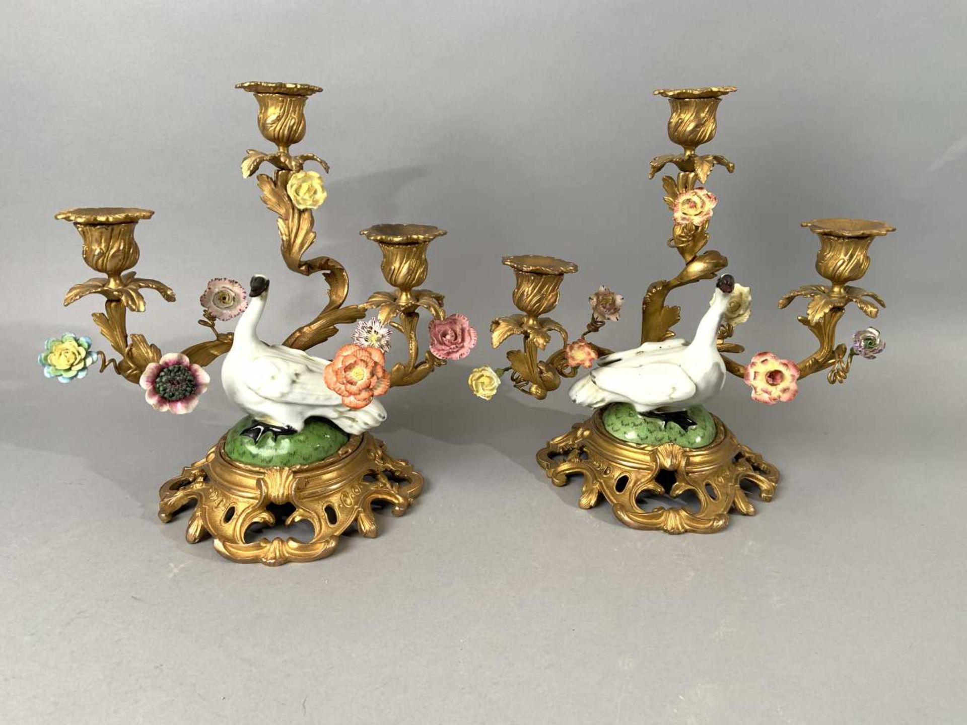 Paire de cygnes en porcelaine polychrome. Montés en candélabres à trois lumières ornées de fleurs en