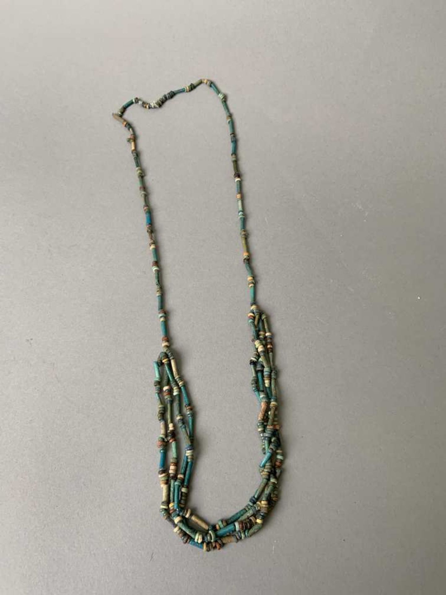 Collier composé de perles tubulaires en faïence émaillée, il est terminé par quatre rangs de perles.