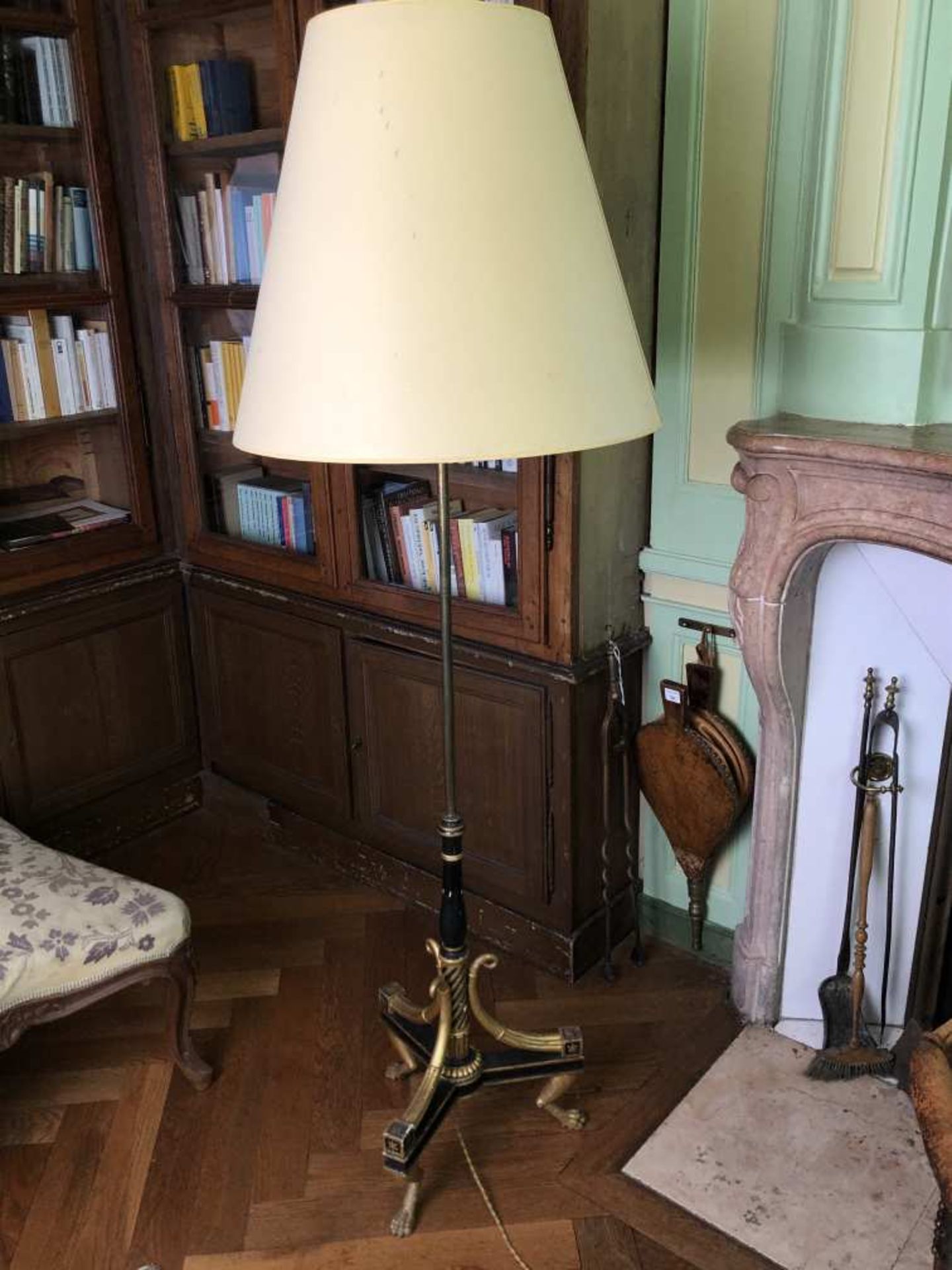 Lampadaire à pied en bois noirci et doré reposant sur trois pieds griffes, fût en laiton terminé par