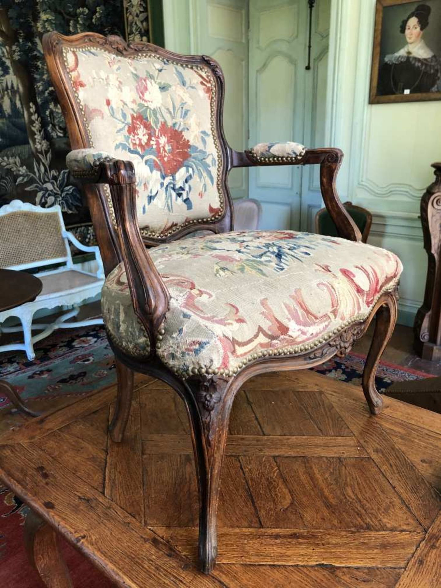 Fauteuil en hêtre sculpté et teinté, couvert d'une tapisserie à fleurs du XVIIIe siècle. Style Louis