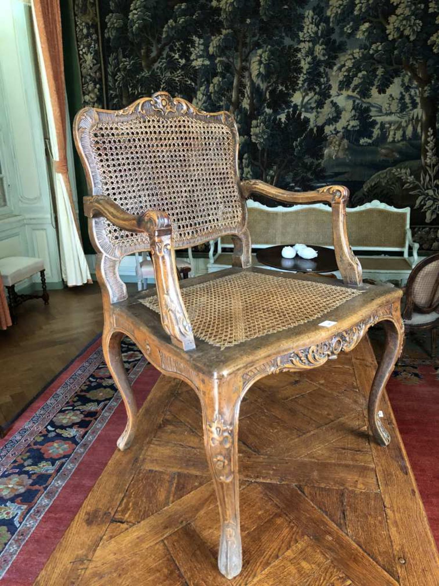 Fauteuil en hêtre sculpté de feuilles d'eau, agrafes et feuillages, sur fond de croisillons et