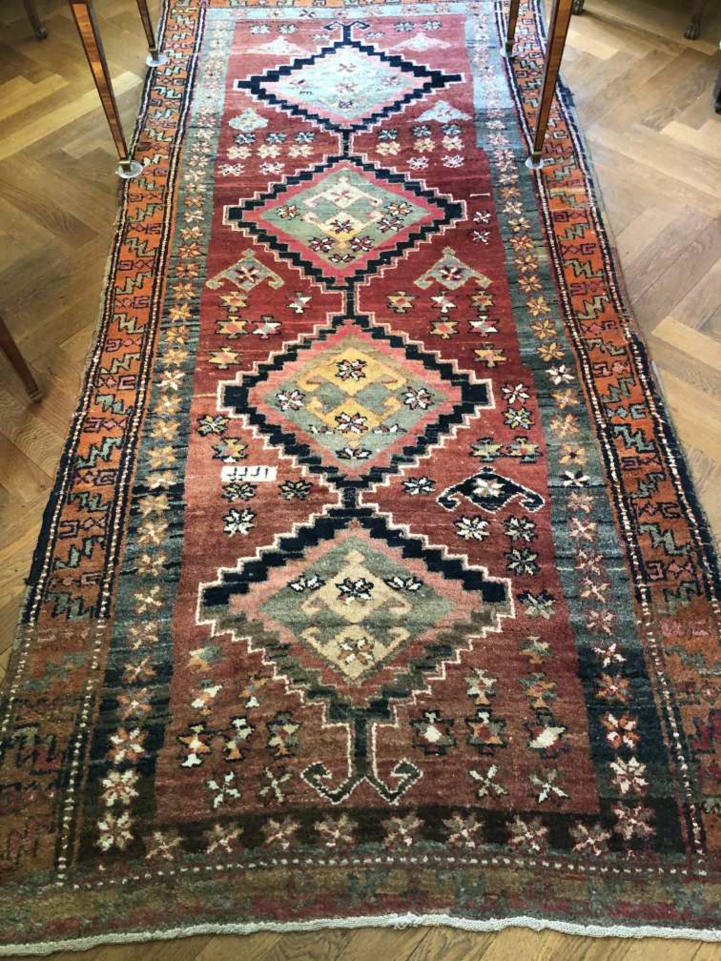 Tapis en laine à décor de quatre médaillons. 306 x 146 cm.