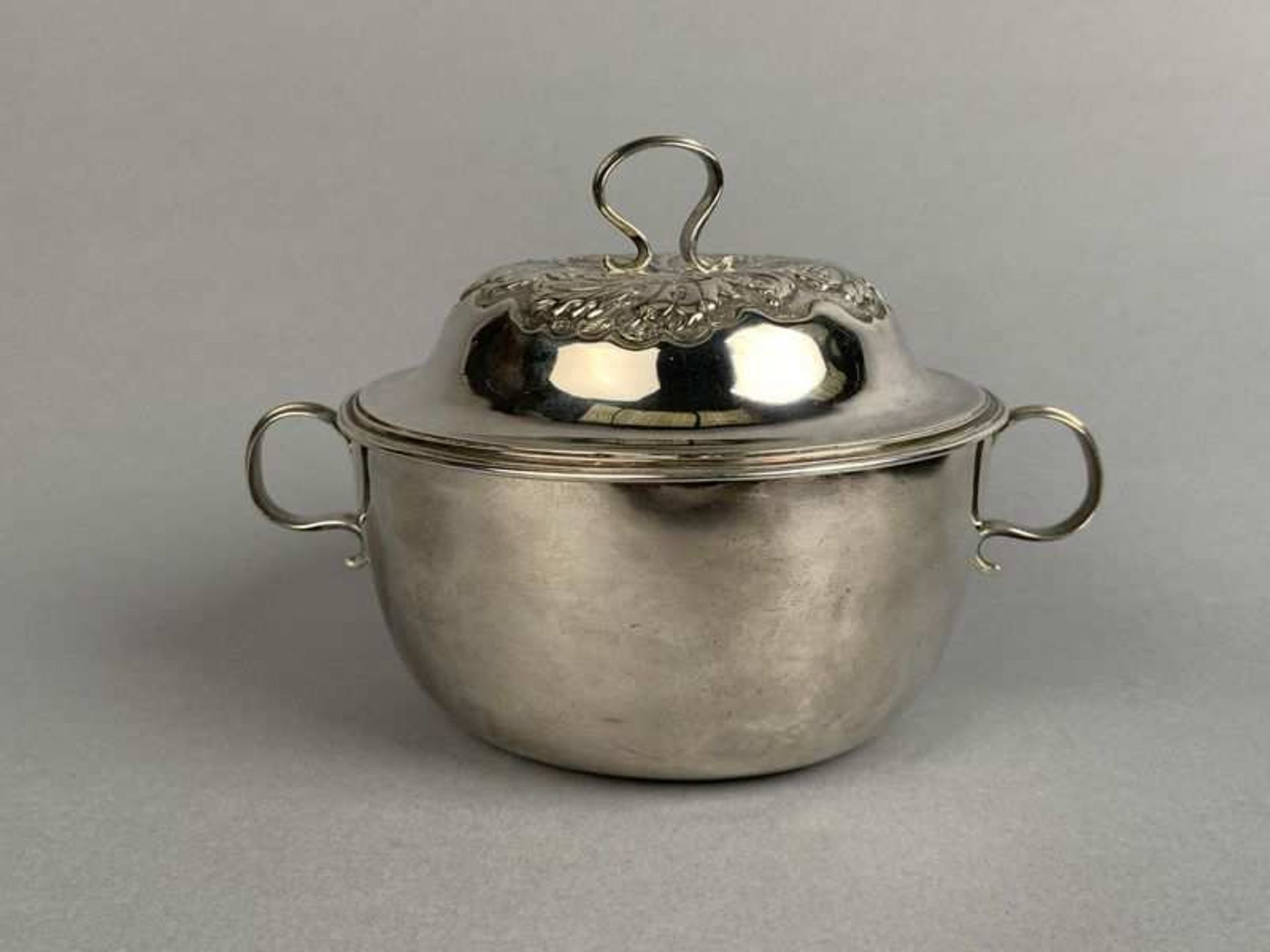 Rare bouillon couvert en argent à corps uni. Prise et anses en volute à filets. Couvercle mouluré,