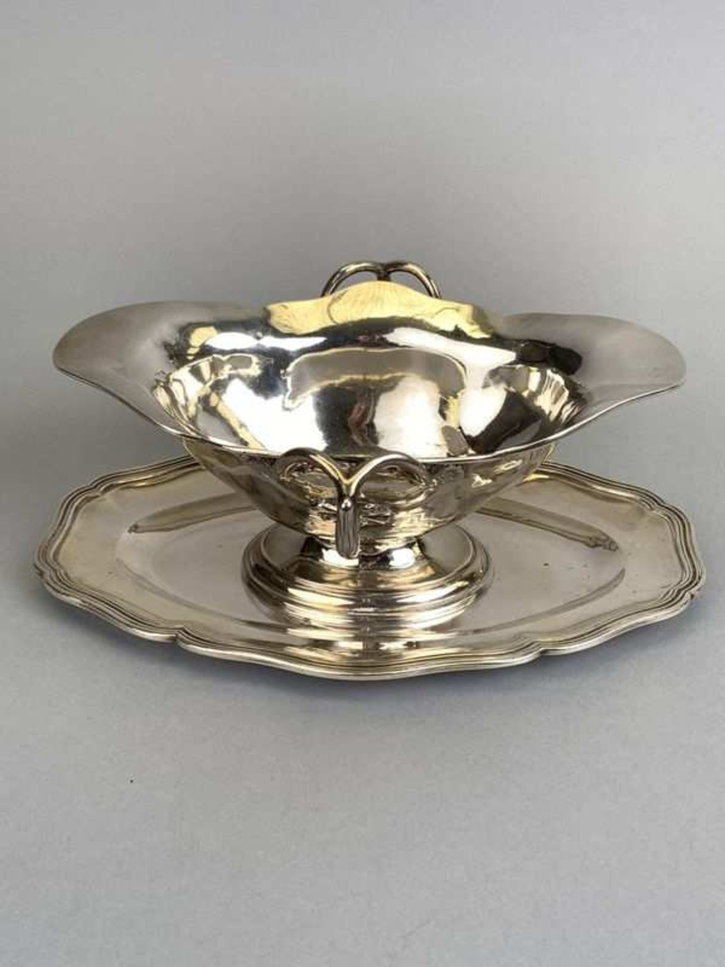 Saucière en argent Minerve à contours, modèle à filets. Anses à trois appliques feuillagées. P.