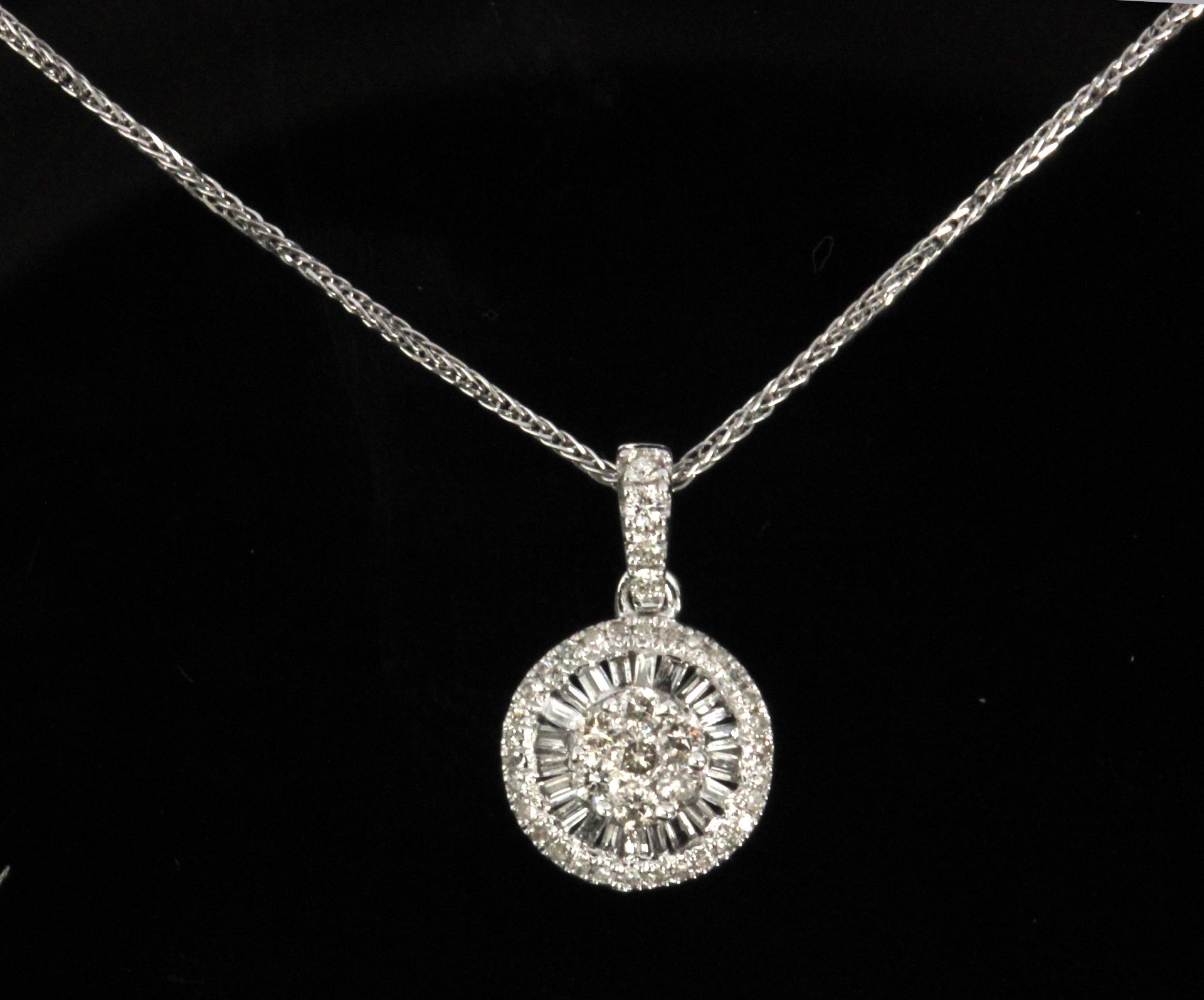 A diamond cluster pendant with baguette cut and brilliant cut diamonds in an 18k. white gold setting