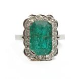 An emerald and diamonds cluster ring with an 18k. white gold setting