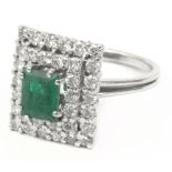 An emerald and diamonds cluster ring with an 18k. white gold setting