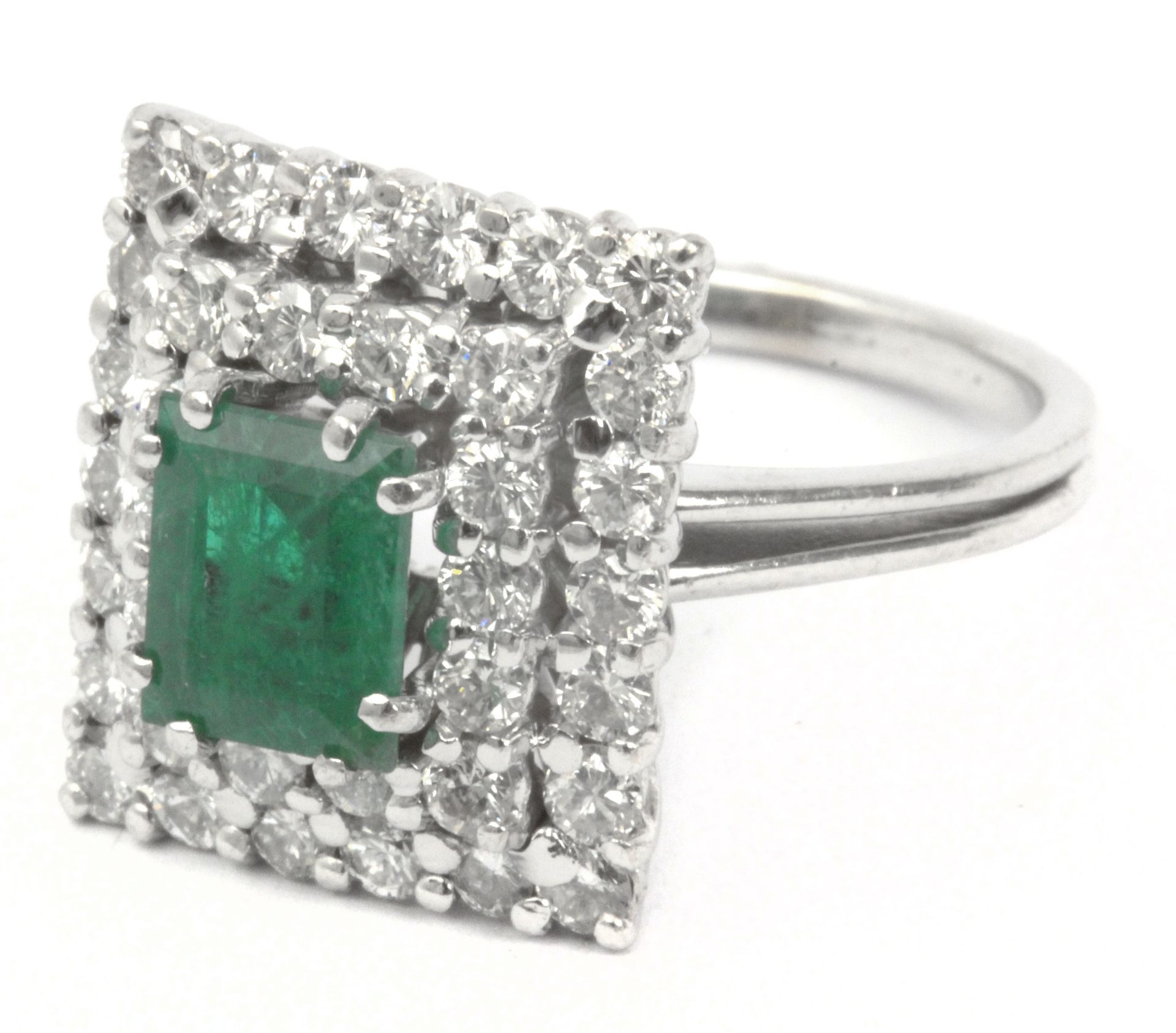 An emerald and diamonds cluster ring with an 18k. white gold setting