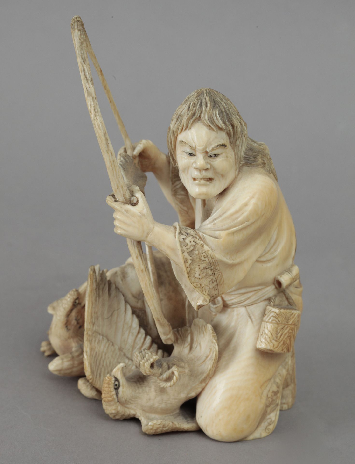 19th century Japanese school. A carved ivory okimono depicting a hunter with his arch