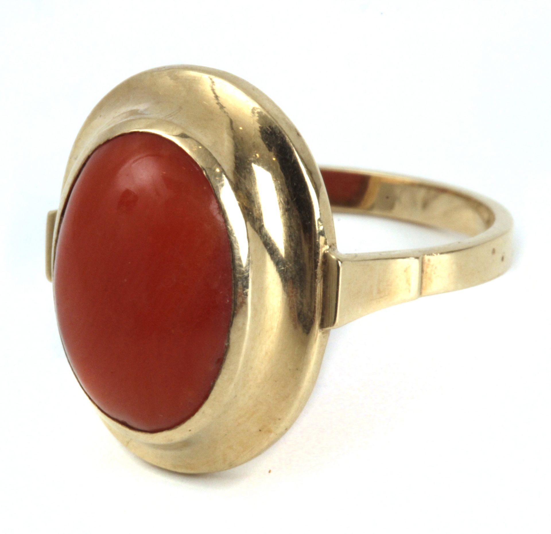 A ring circa 1950 with an 18k. yellow gold setting with an orangy coral oval cabochon