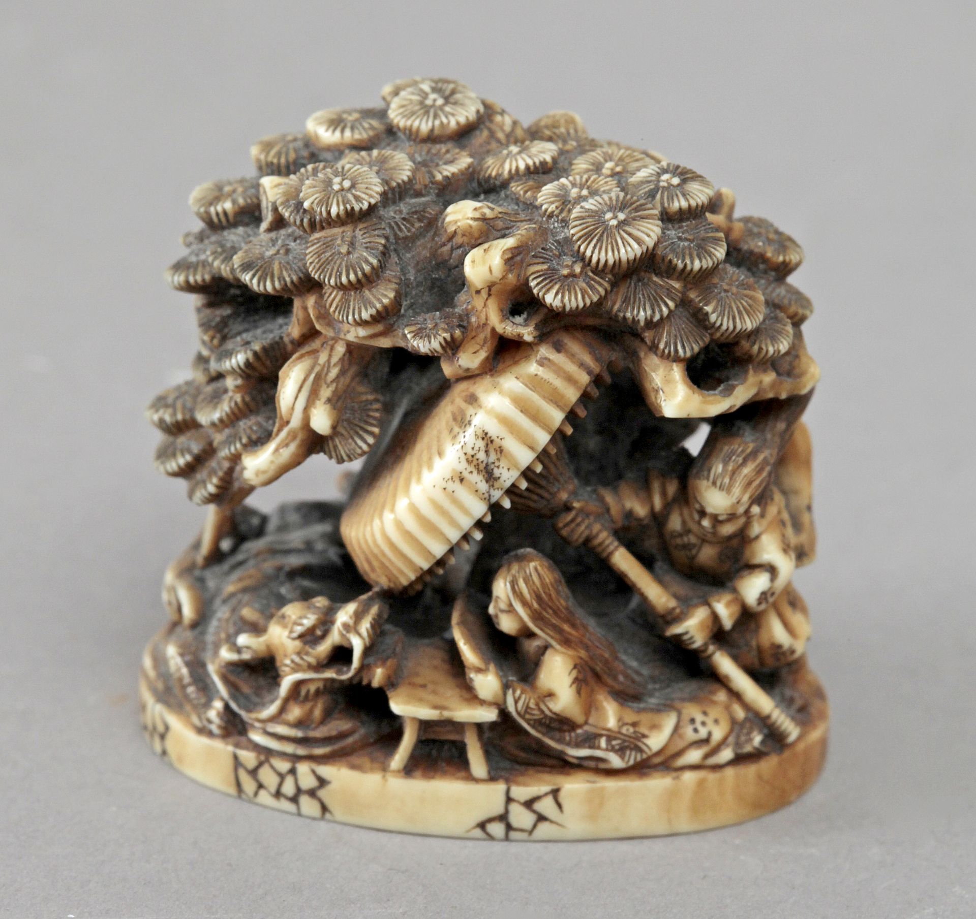 Late 19th century Japanese school. A carved ivory netsuke okimono depicting a group of figurines