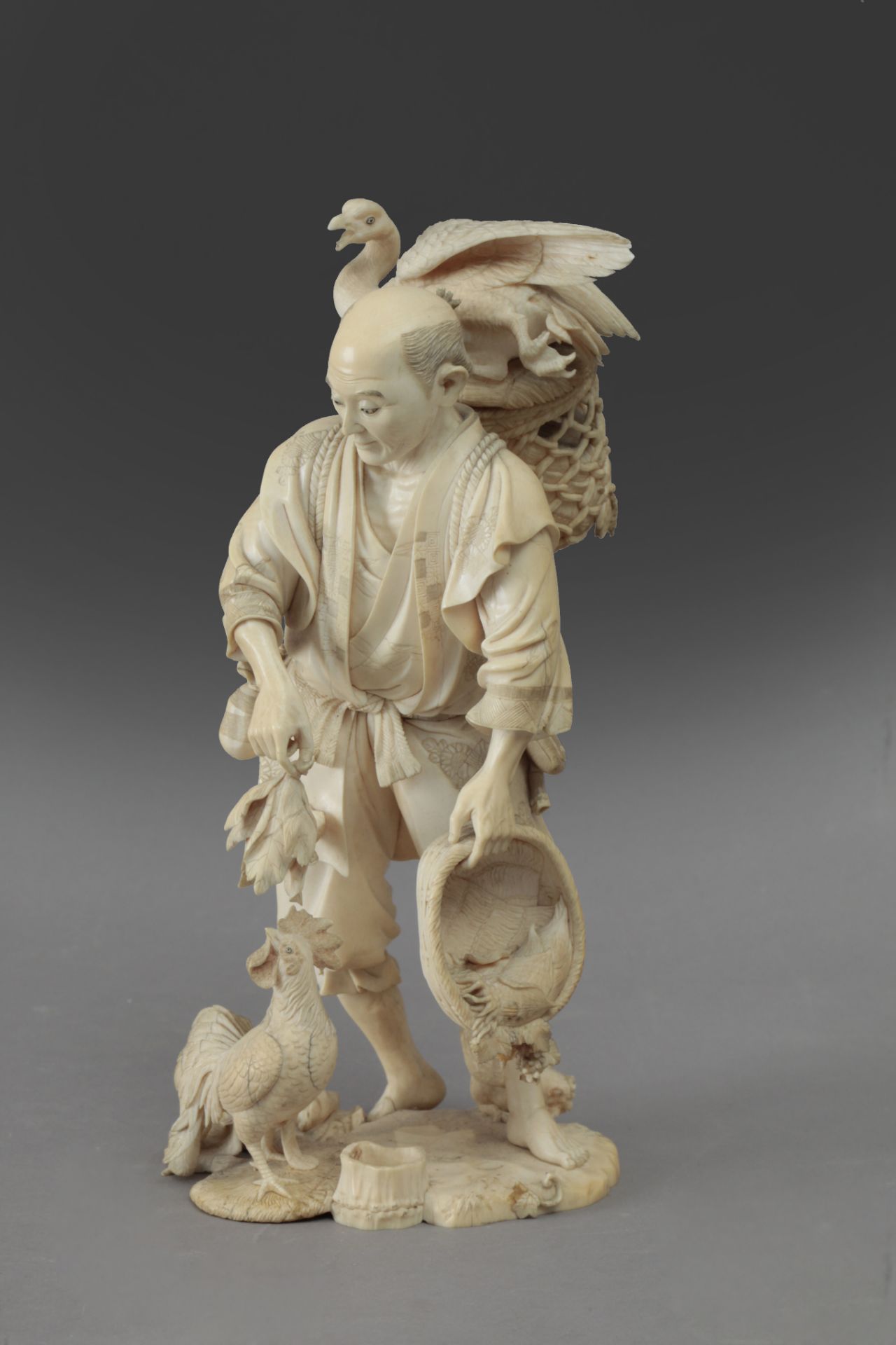 Late 19th century Japanese school. A carved ivory okimono depicting a farmer feeding birds. Signed