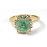 An emerald and diamond cluster ring with an 18k. yellow gold setting
