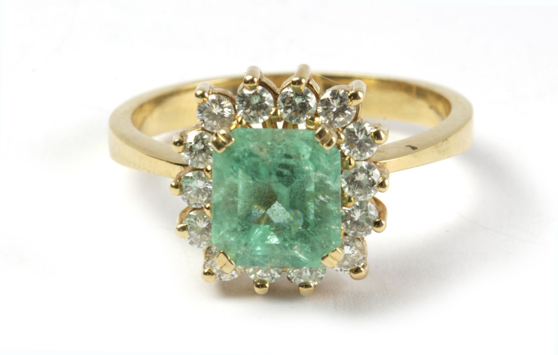 An emerald and diamond cluster ring with an 18k. yellow gold setting