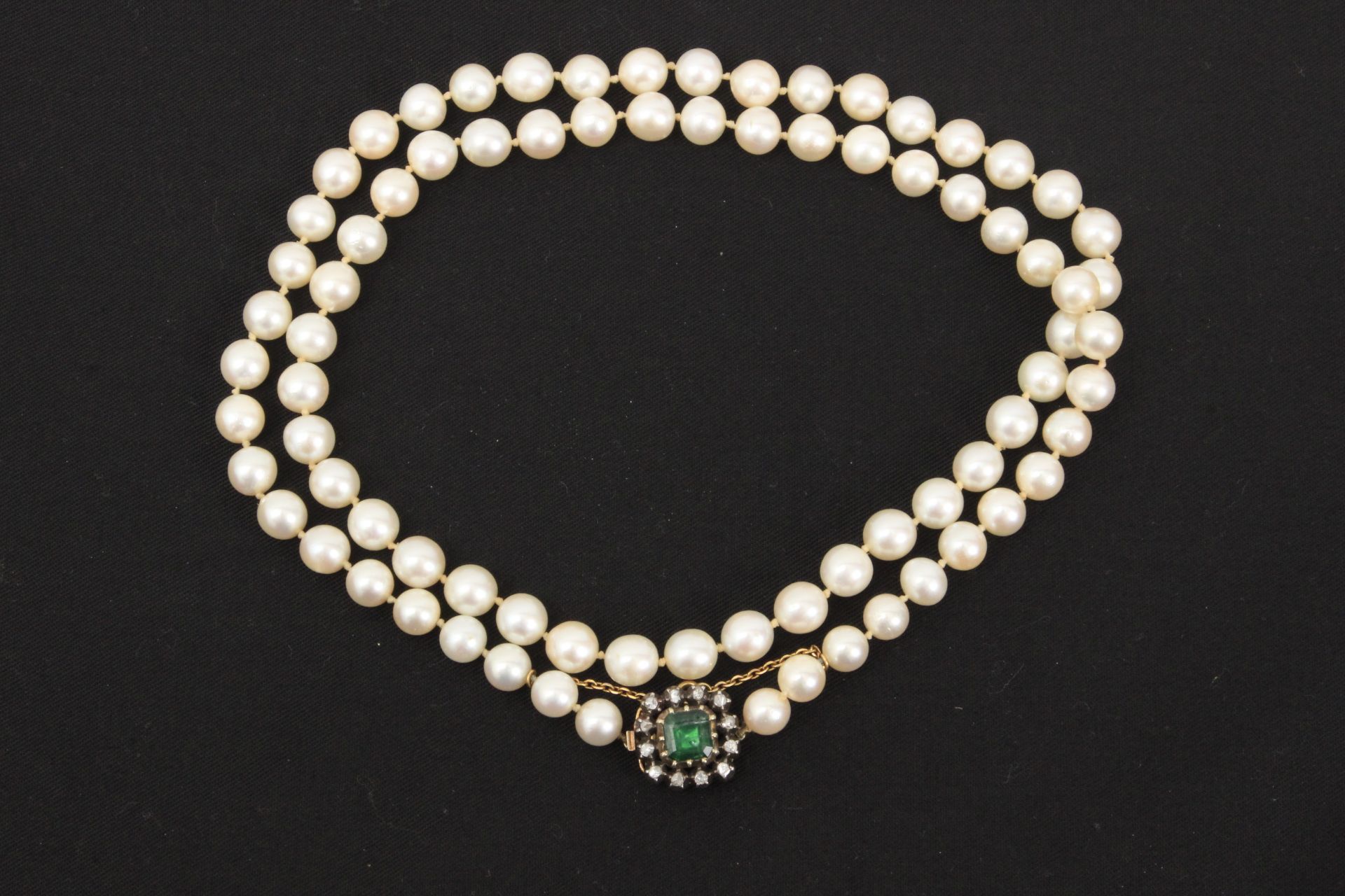 A cutured pearl necklace with an emerald and diamond brooch clasp