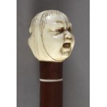 A late 19th century walking cane in carved walnut and ivory