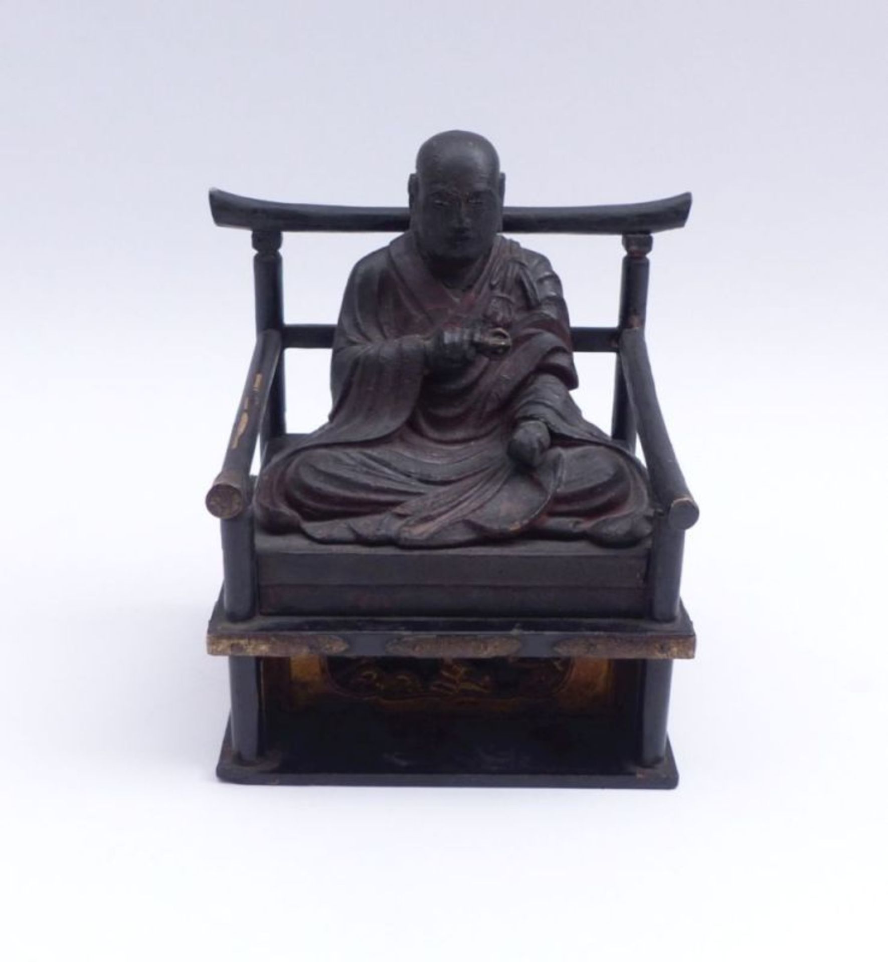 Auf Thron sitzender Lama mit VajraTibetAuf einem Armlehnstuhl über hohem Sockel sitzender