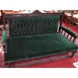 An Edwardian Ebonised Couch with green upholstery.